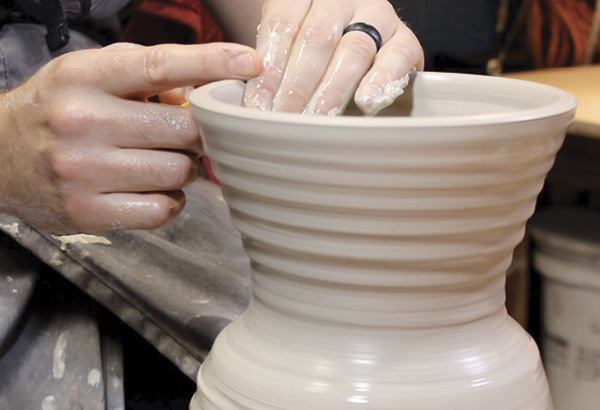 1 Thicken the rim of a bowl, thrown off the hump, using the pointer finger of your right hand while the first finger and thumb of your left hand support the clay wall.
