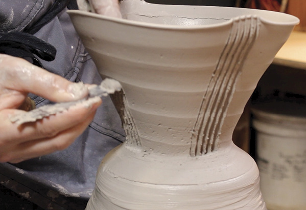 3 Taking a piece of an old tiling trowel, carve a series of vertical lines into the freshly thrown bowl, creating a series of four quadrants.