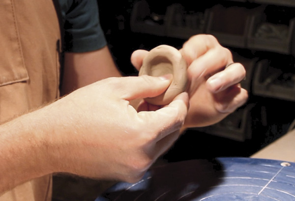 19 Take a golf ball-sized amount of clay, pinch a small bowl between your thumb and fingers. When you are ready, score, slip, and attach the bottom of the pinched bowl to the curved neck of the ale bowl.