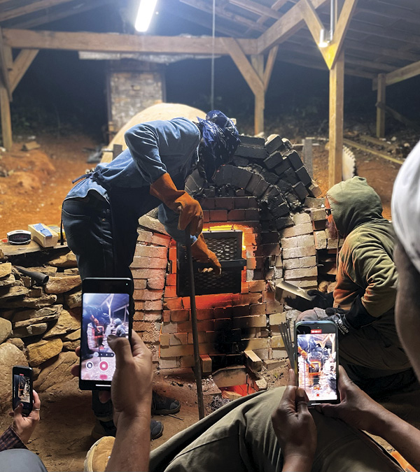 13 Other residents watching as Johnnie Bess (standing) and Dom Venzant (squatting) brick up the kiln door. Photo: Hambidge Center staff.