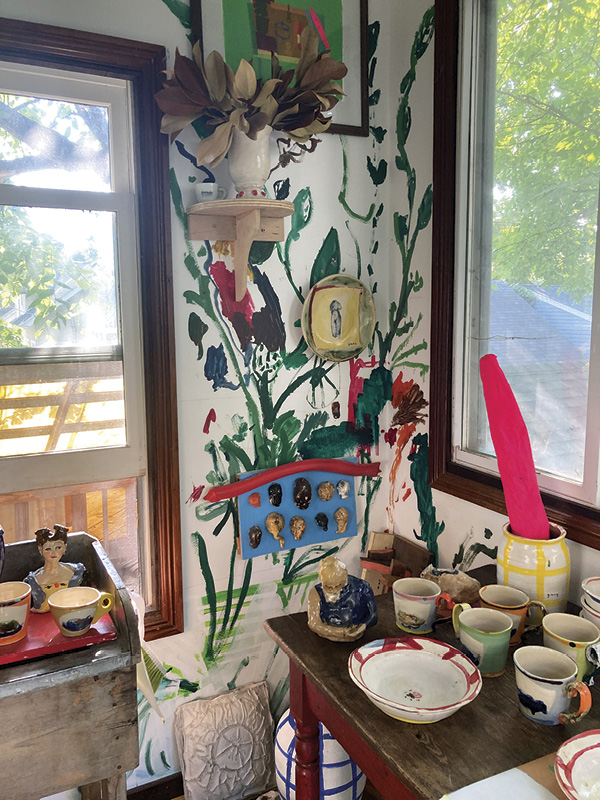 6 Detail of showroom; Sims and her daughter, Ida, painted the floral scene on the wall, while some absurd objects leftover from installations, such as the neon pink paper-mâché baguette, grace the space.
