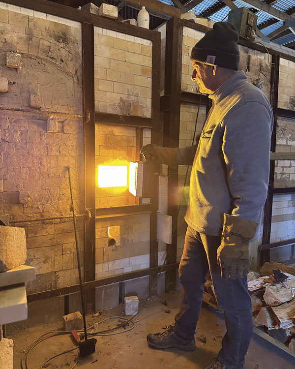 Donovan Palmquist standing in front of a kiln.