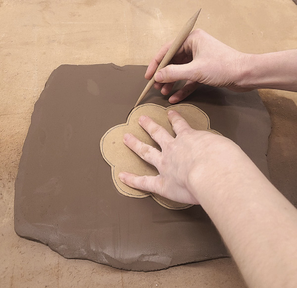 2 Roll out a slab and cut out the shape of your base using a template as a guide.