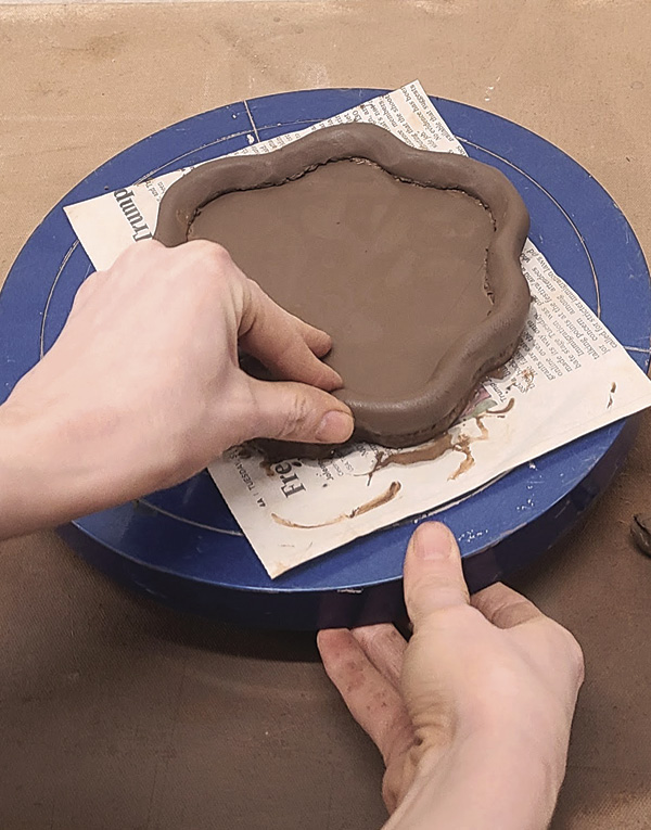 5 Pinch and press the coil into the scored edge to create a skirt or decorative foot.