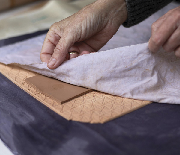 3 Cover the clay slab with a piece of fabric before embossing.