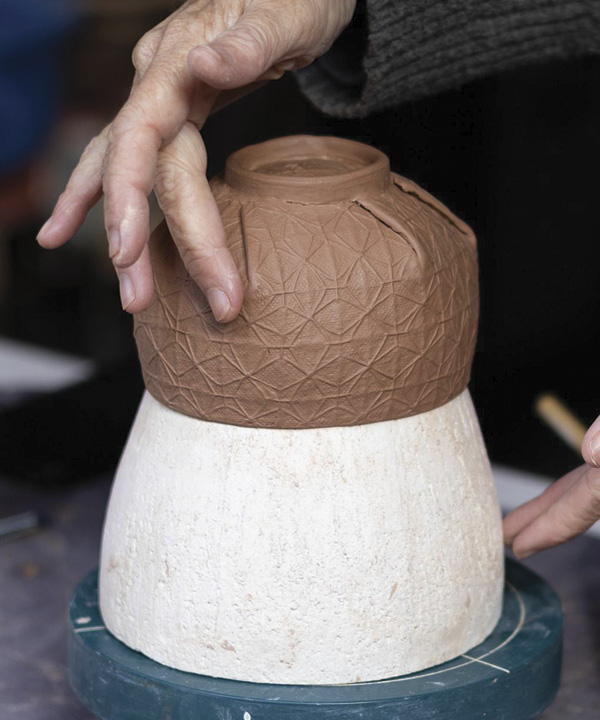 18 Attach the foot ring while the cup is still on the form and use your finger to smooth the pleats.