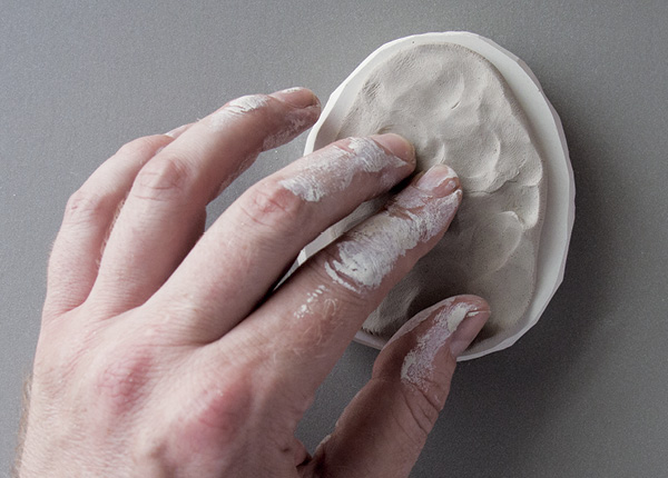 4 When the plaster is dry, press clay into the mold cavity with your fingers.