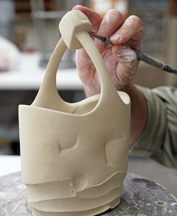 15 With the final handle shape established, cut at the top and attach the finial. Make sure to poke a hole for air to escape in the finial, and compress the seams of the attachment with a rubber tool or stylus.