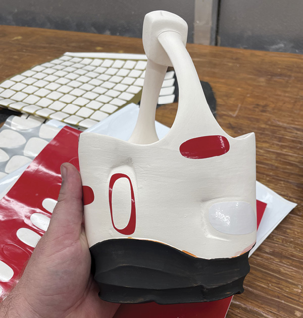 17 After the final bisque firing, apply vinyl stencils to the piece in relationship to the stamps.