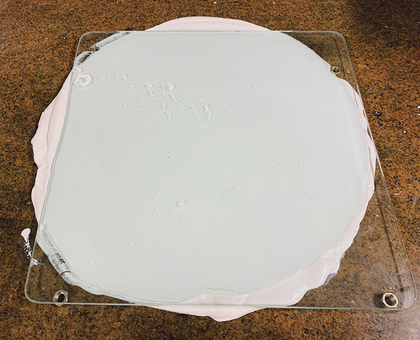 1 Making a perfectly flat plaster slab with a glass slab and four nuts on a non-porous surface.