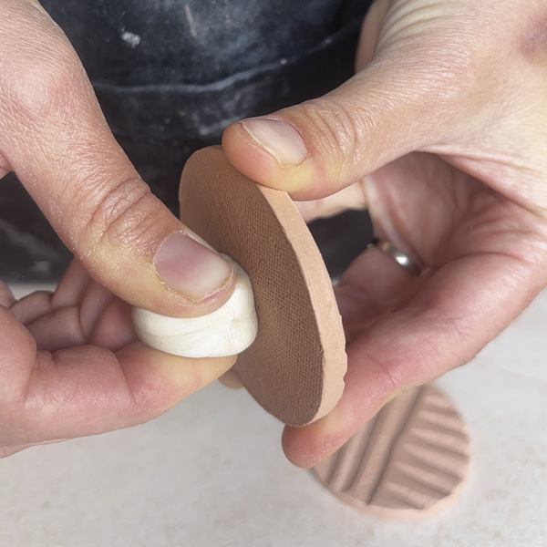 1 Apply a cylinder of putty to the back of a bisque-fired ornament.