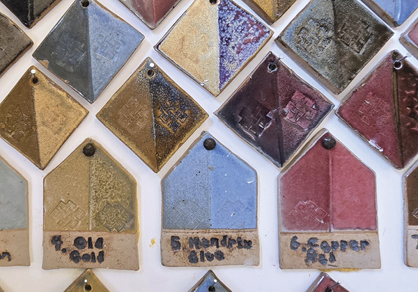 3 The base glaze tiles are affixed to the wall. Follow Old Gold up to the right and Hendrix Blue to the left to find the result of each glaze layered over the other, with stamped textures showcasing how each glaze breaks and pools.