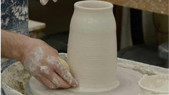 Neil Estrick shows how he holds a sponge when throwing a vase on the pottery wheel