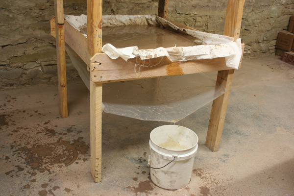 3 The gravity filter press in action. Water drips out of the slip and through the bedsheet, catches on the plastic, and drips into the bucket.