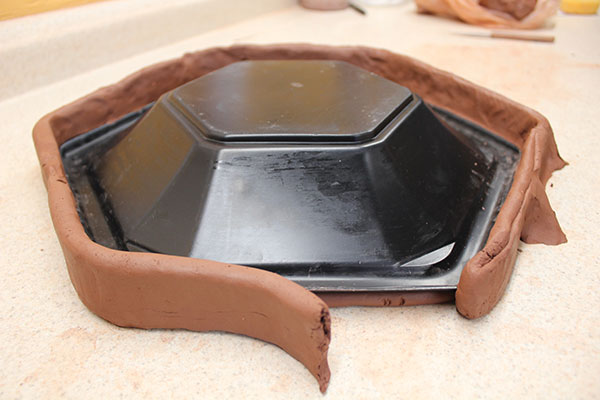 1 Secure the model to the table with clay, then build slab walls around the perimeter and reinforce with buttresses.