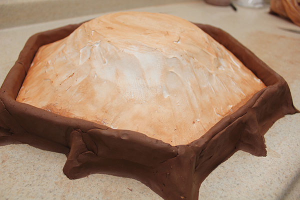 2 Pour liquid plaster over the model. When it starts to set up, manipulate it to mound up evenly over the model.