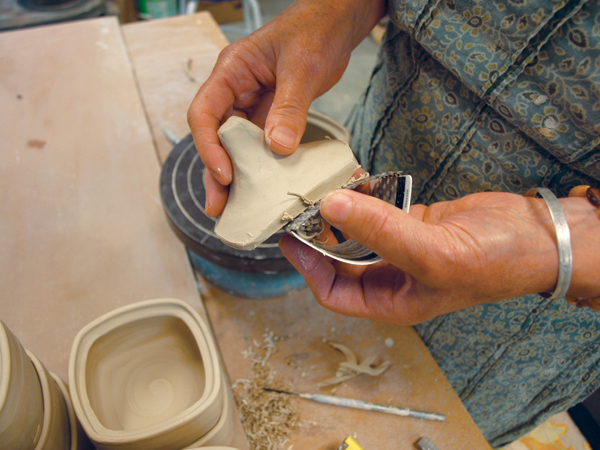 1 Using a Surform to remove excess clay from the lid made for a squared, wheel-thrown form.
