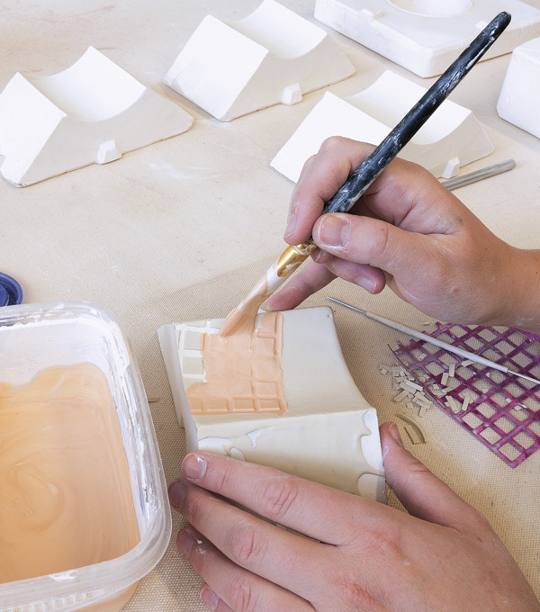 3 Carefully inlay colored casting slip into the incised lines of the pattern using a soft brush.