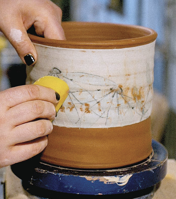 3 Once the slip and the piece are at a similar dryness, apply the transfer and rub it into the piece using a rubber rib.