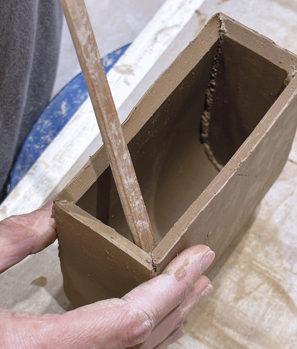 6 Using a right-angle-edged wooden tool, smooth and blend the excess slip on the interior of each seam.