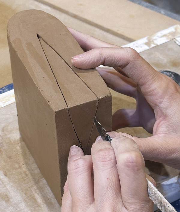 10 With a sharp knife, cut along your marked line keeping your tool perpendicular to the clay surface.