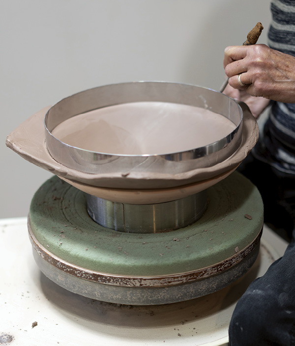 1 Use a rib to smooth and compress the slab into the bisque form. Cut the slab into a circle using a cake ring as a guide.