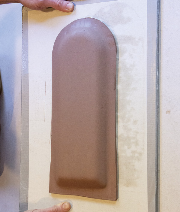 5 Drop the clay and mold on the board to slump it. Trim the clay around the mold.