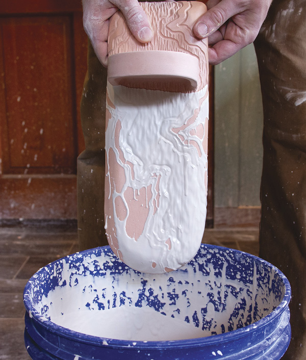 16 Dip the sconce in glaze, then remove any glaze that pools on the waxed areas.
