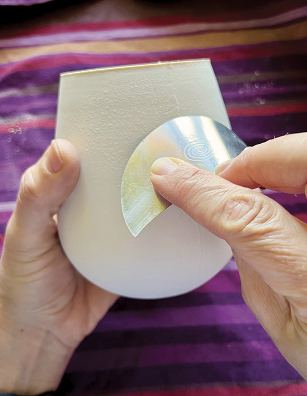 3 Once removed from the mold, use a metal rib to scrape the seams of the cup.
