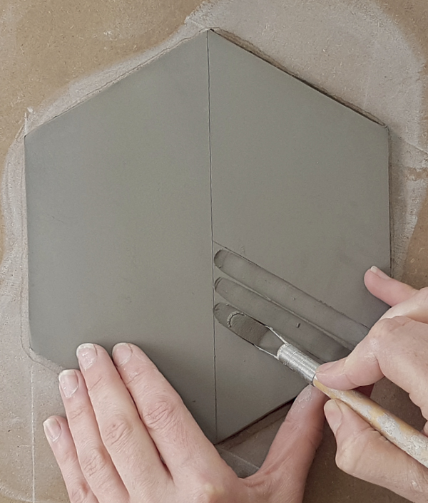 9 Use your loop tool to carve the first section, and support the edge of your tile with your thumb.