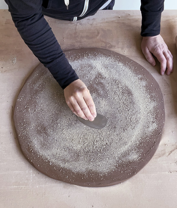 2 Roll out a slab, cut to slightly larger than your slump mold, and cover one side with grog. Compress with a rib.
