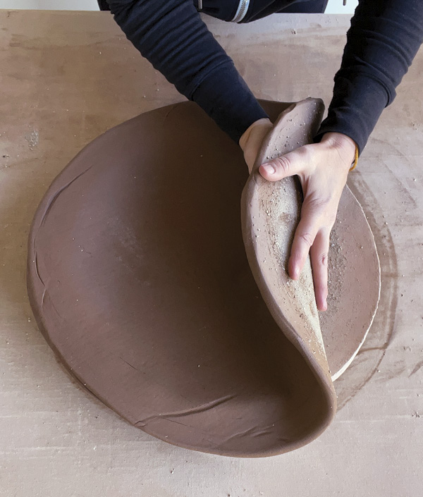 3 Lay slab gently, grog side down, into curved slump mold that has been sprinkled with grog.