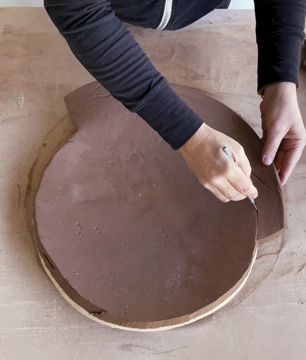 4 Trim the base of the vessel, now formed  in the slump mold, to size and compress the slab with a rib.