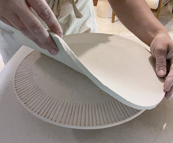 2 Lay the clay circle onto a hump mold. This one is made of bisque-fired clay with a carved texture added around the rim.