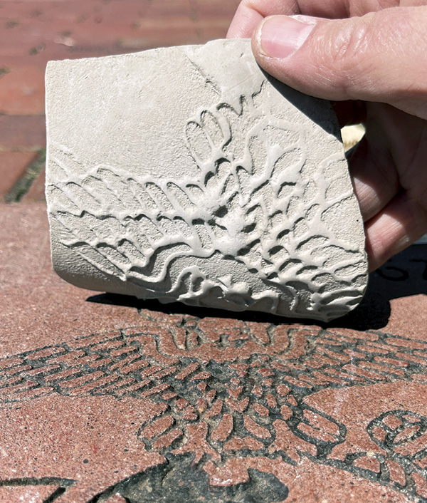 5 Pull out the clay slabs and neck. Leave the candy box in sight. Press the clay slab into the texture and peel back.
