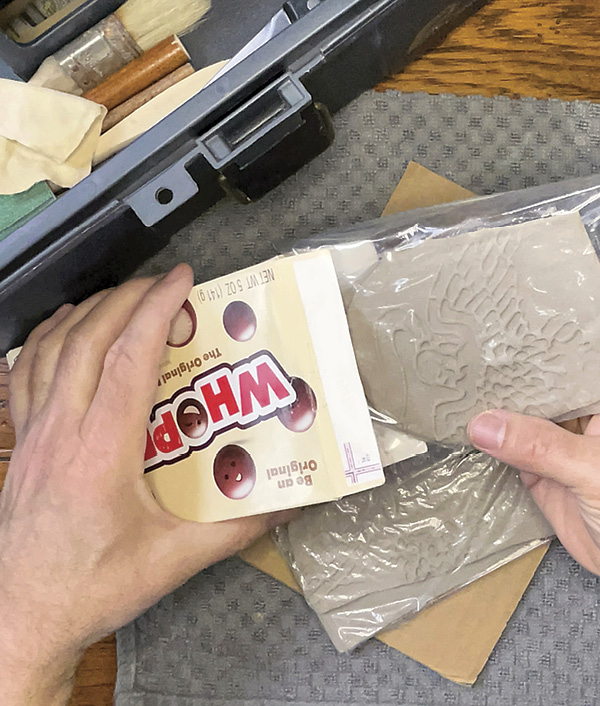 7 Back at your workspace, remove your plastic-wrapped clay impressions from the candy box.