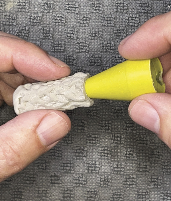 11 Slide the clay neck off the brush handle. Smooth the neck opening. Use a small conical form to round the openings.