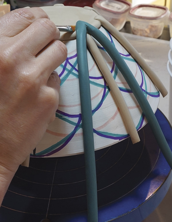 5 Start attaching the colored coils, scoring and compressing the seams.