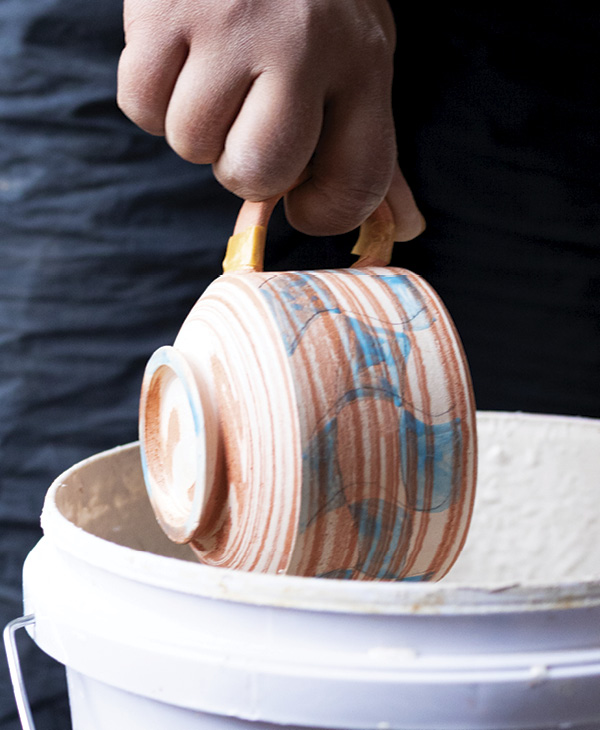 10 While holding the handle, dip the pot in a glossy white glaze.