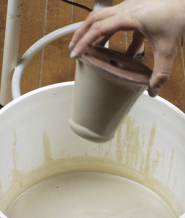 12 Dunk the shakers, top first, into a bucket of white slip. Avoid getting any slip on the bottoms. Set them aside to dry.