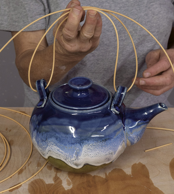 1 Pass the cane through both lugs, pull up in the middle, then loop the cane from both sides over the top of the teapot.