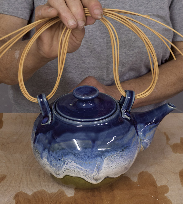 2 Cut five lengths of round cane, then pass them through the lugs and over the top to create the skeleton handle.