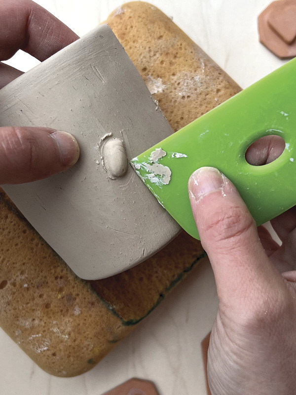 4 Using a rib or wooden knife, smooth the clay around the attachment to seal.
