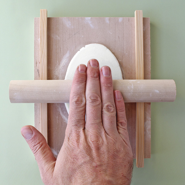 2 Roll a slab of clay between thickness strips on a dampened wood board.
