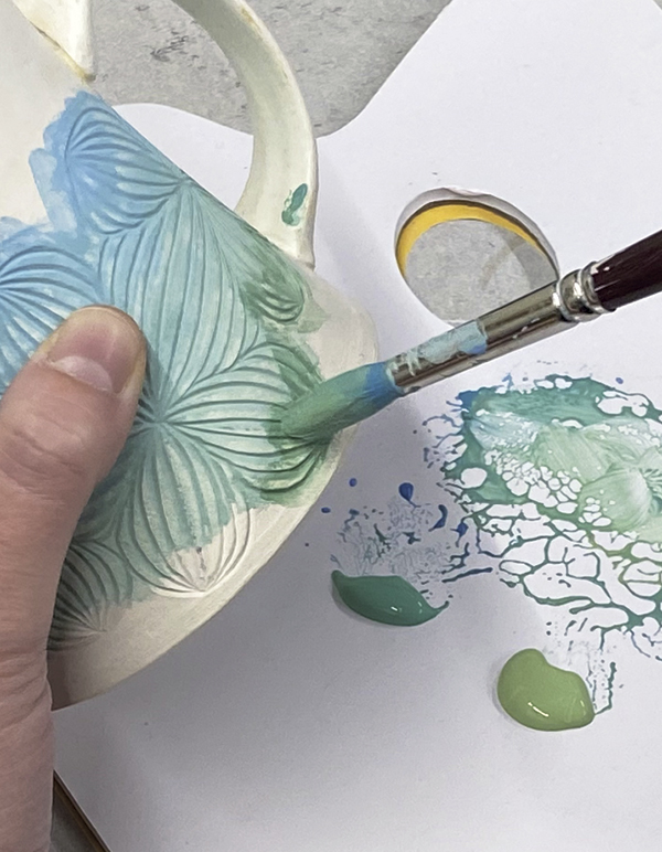 5 Apply 2 coats of underglaze over the carved areas, blending colors together.
