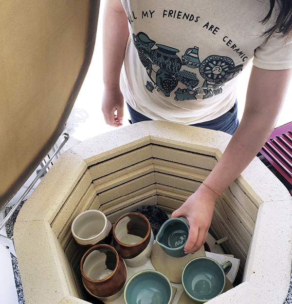 Kiln owner unloading glazed ceramics. Photo: @curvypotshandmade**