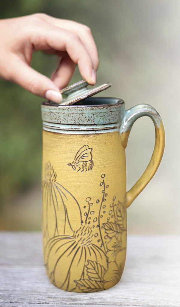 Dault Pottery's Wildflower travel mug, 61/2 in. (16.5 cm) in height, dark brown stoneware, yellow underglaze, 2024.