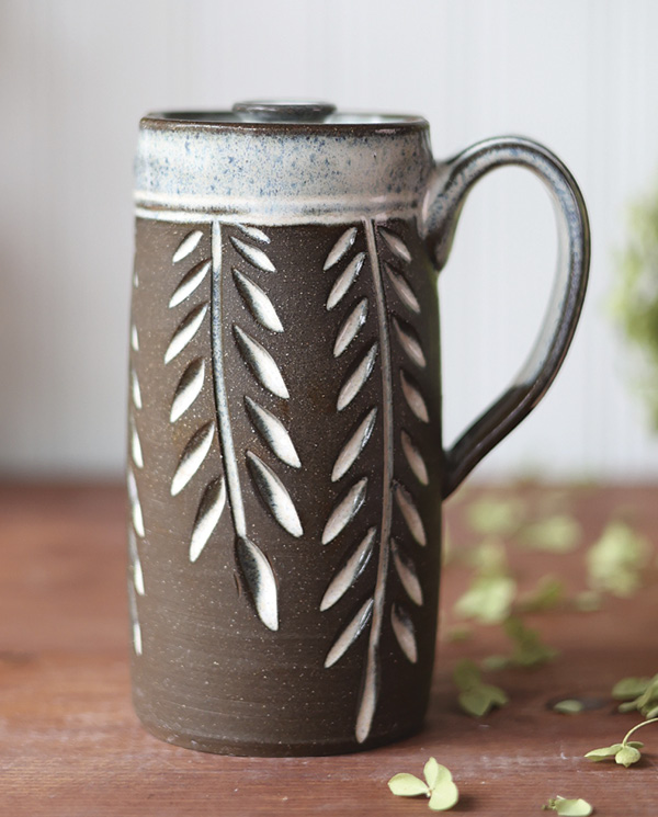 Dault Pottery's Vine-carved travel mug, 61/2 in. (16.5 cm) in height, dark brown stoneware, white glaze, 2024.