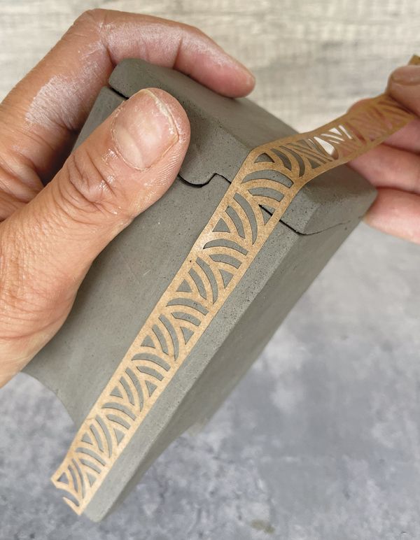 7 Attach a pre-cut paper stencil with a slightly wet sponge.