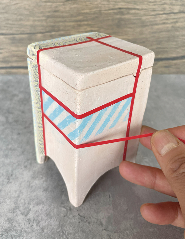 13 Bisque fire the dried form, then lightly sand the box. Apply underglaze transfers and resist tape.